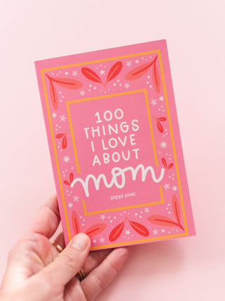 Hand holding a pink '100 Things I Love About Mom' prompted journal by Pippi Post
