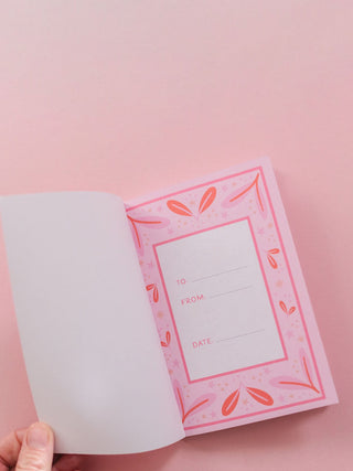 Open pink prompted journal showing To, From, and Date fields with floral border design