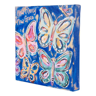 Blue canvas wall art featuring colorful painted butterflies with New Mercy New Grace text