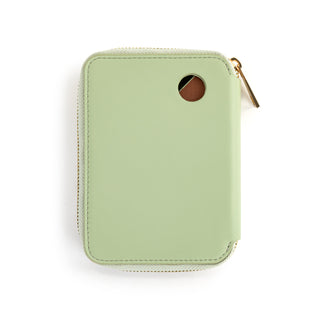 Back view of a sage green zip-around passport wallet with gold zipper and circular cutout window