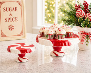 Peppermint swirl cake stands in red and white displayed with holiday cupcakes and decorations
