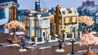 Department 56 Christmas village scene with illuminated houses, trees, and figurines in winter setting