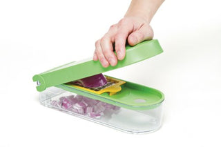 Hand pressing green 3-blade dice and slice chopper cutting red onion into container below