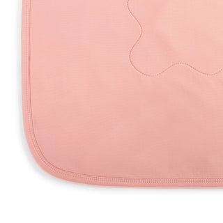 Close-up corner detail of coral weighted cooling lap blanket showing stitched edge binding and quilted design