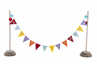 Happy Birthday banner with colorful triangle pennants strung between two wooden posts with pom-pom toppers