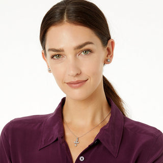 Woman wearing silver Abbey Cross necklace with matching crystal stud earrings over purple collared shirt