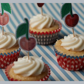 Close up of frosted cupcakes in red white and blue gray gingham liners with cherry toppers