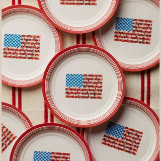 Set of 7-inch patriotic paper plates with floral flag design on striped tablecloth