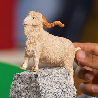 Schleich Angora Goat figurine with curly white wool and brown horns standing on granite rock