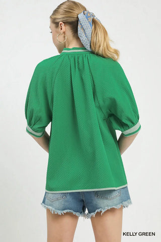 Woman wearing a green blouse with puffed sleeves 