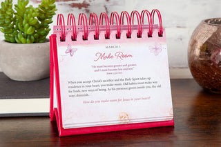 Pink spiral-bound perpetual flip calendar displaying March 1 devotional on wooden desk