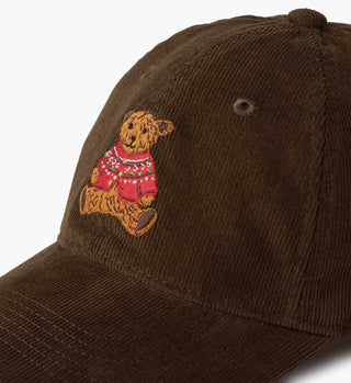 Close-up detail of brown corduroy baseball cap with embroidered teddy bear in Christmas sweater