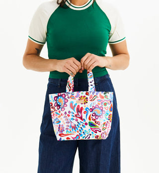 Model holding Consuela Grab N Go Mini tote bag featuring vibrant multicolor abstract print on white background.