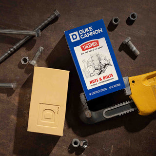 Duke Cannon Nuts and Bolts Big Ass Brick of Soap with packaging surrounded by hardware tools