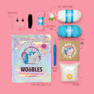 The Woobles Billy the Unicorn beginner crochet kit with all included materials displayed on pink background