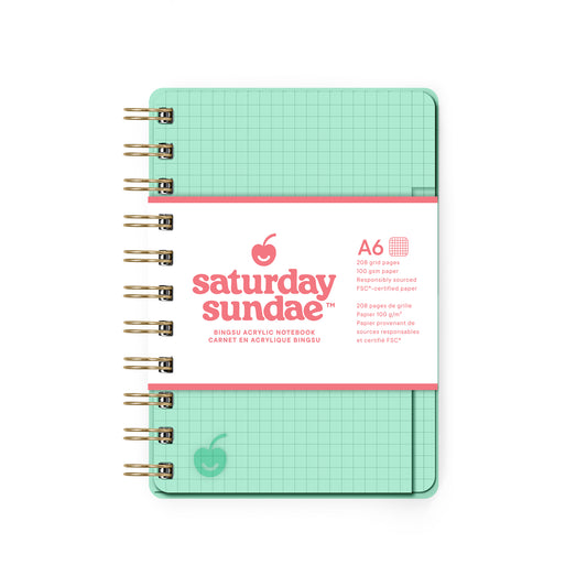 Mint green notebook with grid pattern on a white background, featuring 'Saturday Sundae' branding.