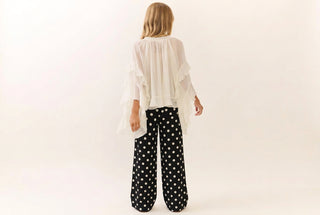 Black wide-leg pants with large white polka dots, shown from behind on a model