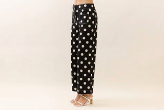Oddi black wide-leg pants with large white polka dots, styled with white heeled sandals.