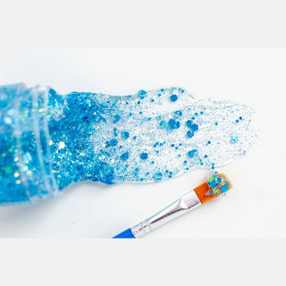 Blue hair glitter gel spilling from jar with electric blue and iridescent particles on white surface