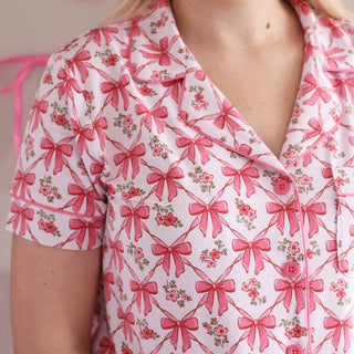 Close-up of pink piping buttons and collar on white bow print pajama top