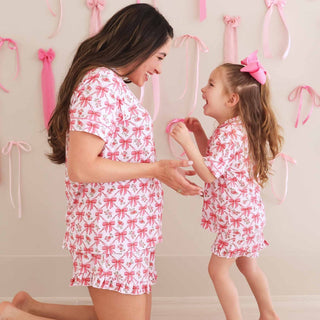 Pregnant woman and daughter in matching pink bow floral pajama sets