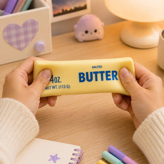 Yellow butter squishy toy held over wooden desk workspace