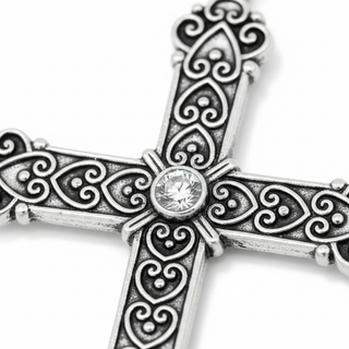 Close-up of silver Byzantium cross pendant showing embossed heart details and bezel-set crystal