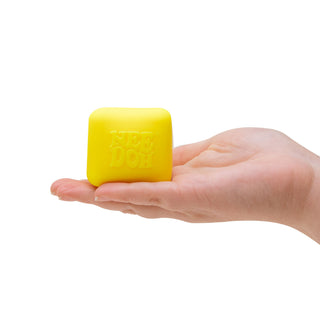 Hand holding a bright yellow cube-shaped NeeDoh stress toy by Schylling