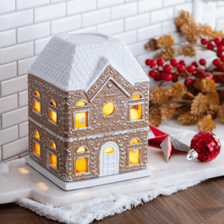 Illuminated ceramic gingerbread house fragrance warmer glowing warmly with holiday decorations