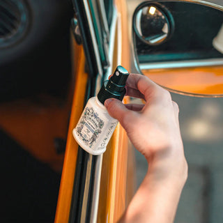 Spraying Car-Pourri fresh air car scent on vintage orange vehicle interior door frame
