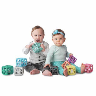Multiple babies playing with teal, purple, and assorted color Malarkey Kids chew cubes with internal dice