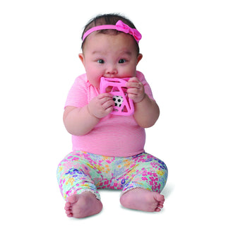 Toddler using bright pink open-frame chew cube with visible white die and textured grip edges