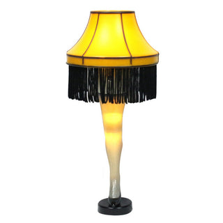 A Christmas Story iconic leg lamp with amber shade, black fringe trim, and illuminated leg base