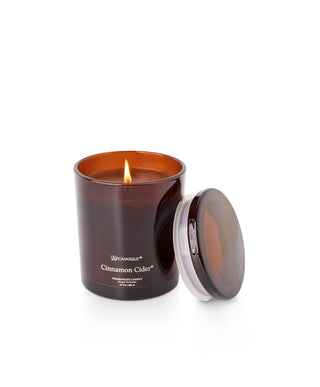 Lit Aromatique Cinnamon Cider 10oz candle showing warm orange flame inside amber glass jar