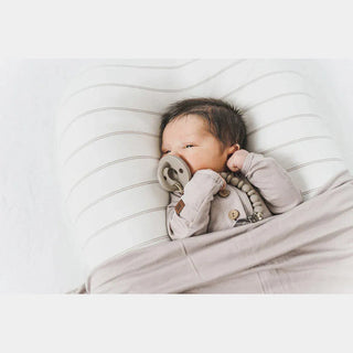 Newborn resting in striped Cocoon Papillon lounger, safe supervised sleep setup with taupe accessories