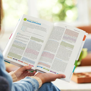 Child holds open Color Code Bible showing Philippians with colorful coded text