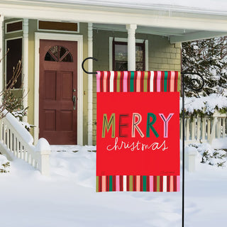 Red garden flag with colorful stripes and Merry Christmas text displayed in snow