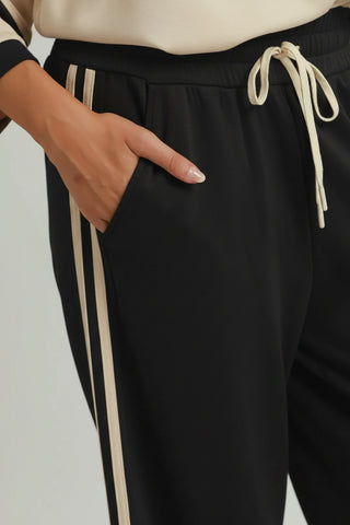 Black straight leg pants with cream side stripes, drawstring waist, and side pocket