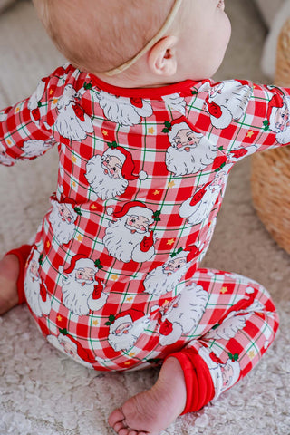 Baby wearing red gingham Santa Claus print bamboo zipper romper, seated view from behind.