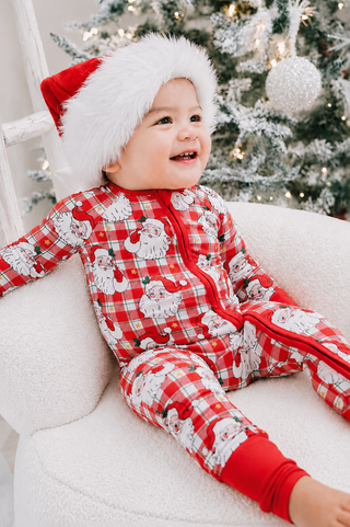 Baby wearing Caden Lane red plaid Santa print zip romper and matching Santa hat