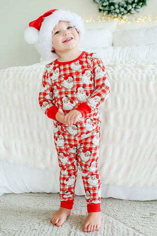 Child wearing red plaid Santa Claus print two-piece bamboo pajama set with matching Santa hat