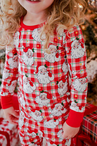Child wearing red plaid bamboo pajama top with vintage Santa Claus faces print