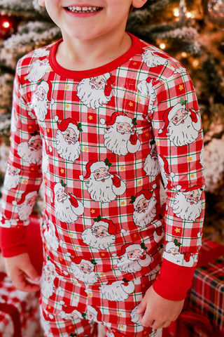 Child wearing red plaid Santa Claus print bamboo Christmas two-piece pajama set near decorated tree