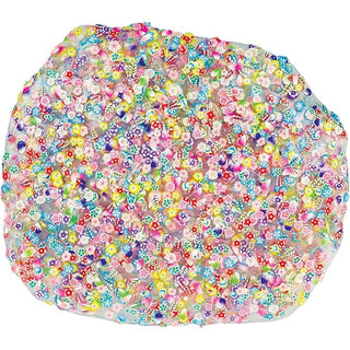 Spread out clear thinking putty on white background densely packed with colorful clay flowers leaves and small animal figures