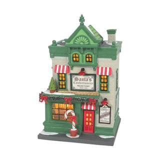 Department 56 Santa's Corner Confectionery miniature with beige brick walls, green trim, and illuminated windows