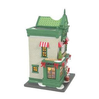 Side view of Department 56 Santa's Corner Confectionery showing forest green trim and glowing yellow window panes