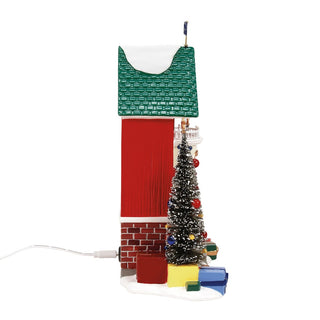 Department 56 Snwvl Sentry Christmas village building with green roof, brick base, decorated tree, and colorful gifts