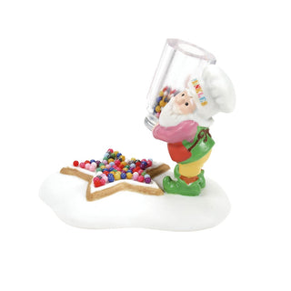 Department 56 elf figurine pouring colorful sprinkles onto a star-shaped cookie decoration