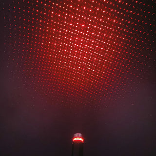 Red laser star projector casting hundreds of glowing red dots across a dark ceiling
