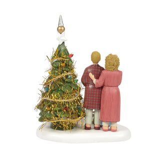 Ceramic figurine of couple in robes admiring decorated Christmas tree with gold tinsel